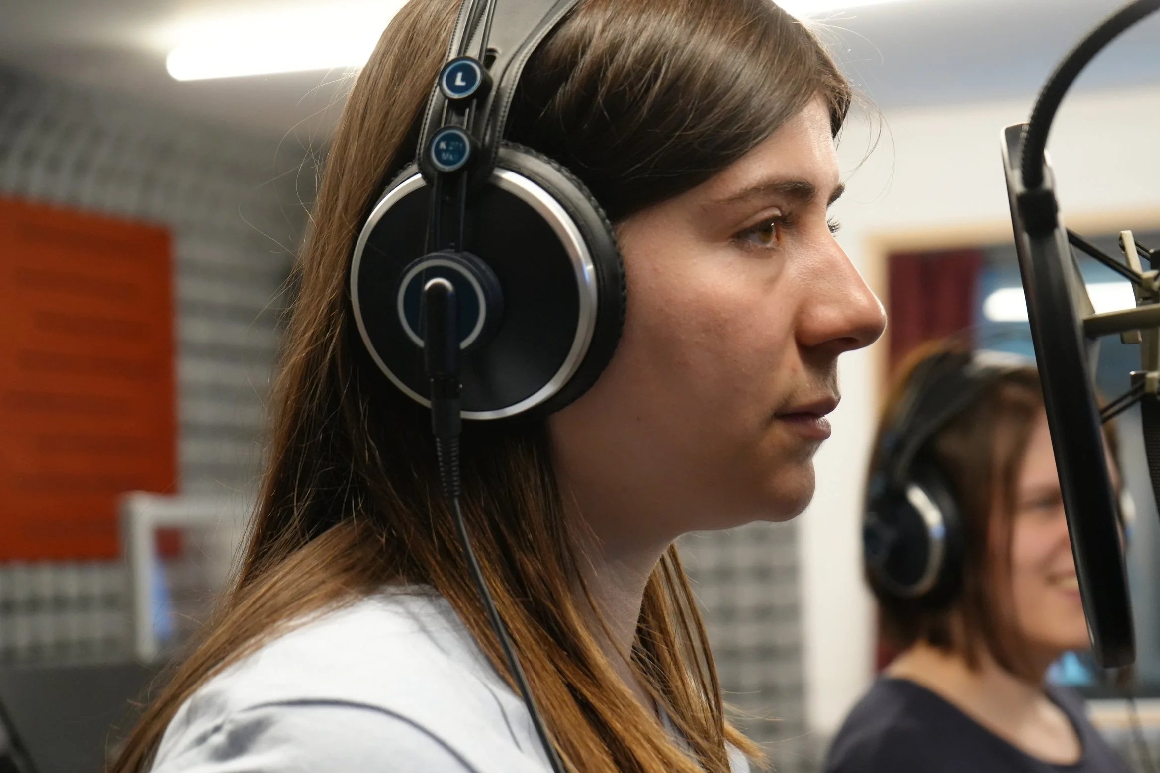 Schauspielerin Luana Roth - Zwei Frauen tragen Kopfhörer und sprechen in ein Mikrofon in einem Tonstudio. Synchronsprecher.