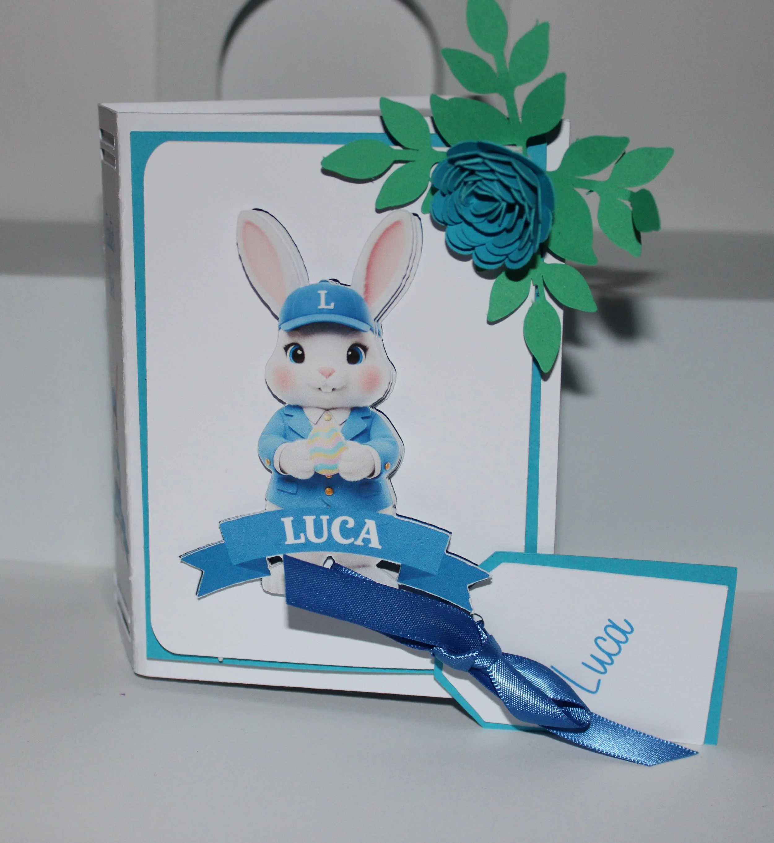 Easter Gift Box For Him! 
Easter gift box shaped like a book, handcrafted with care and charming details. The cover features an AI-generated bunny illustration, precision-cut and layered for a dimensional look. Delicate paper flowers cluster in the t
