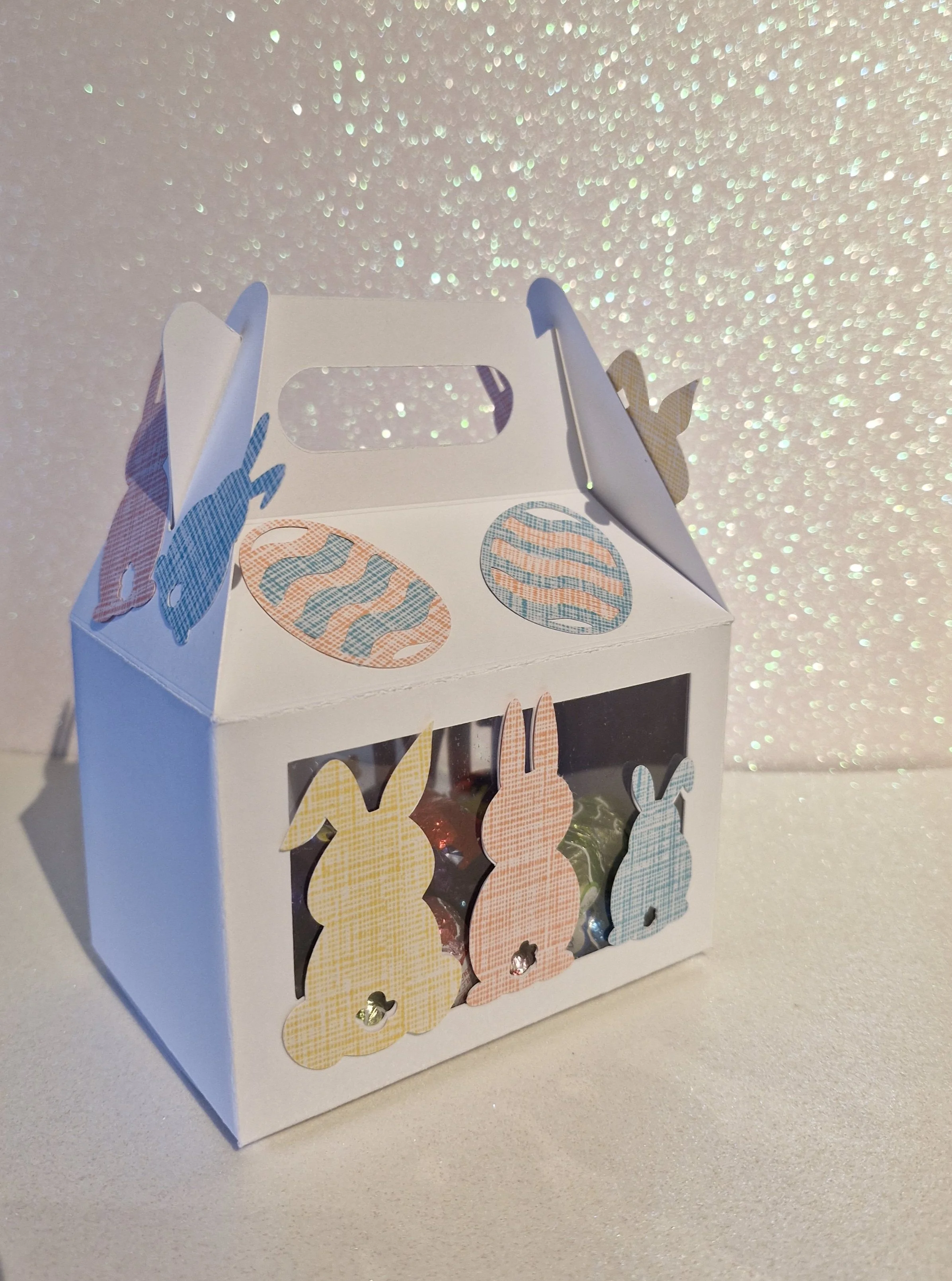 Delicate small butterflies affixed to the box surface, arranged to appear as if they are fluttering above the name.
