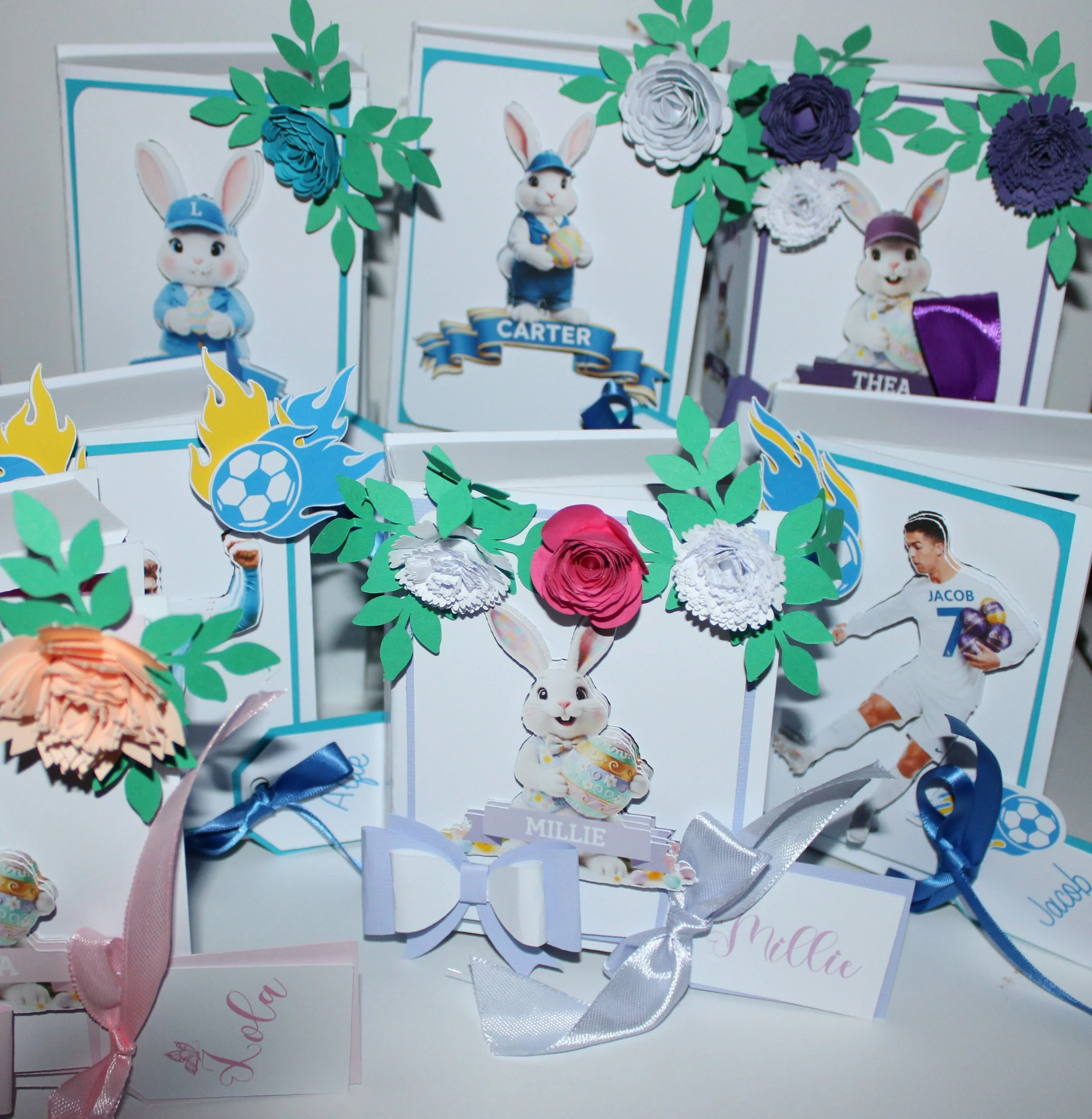 Easter gift boxes shaped like books, handcrafted with care and charming details. The covers features AI-generated bunny illustrations, precision-cut and layered for a dimensional look. Delicate paper flowers cluster in the top corners, while a neat b