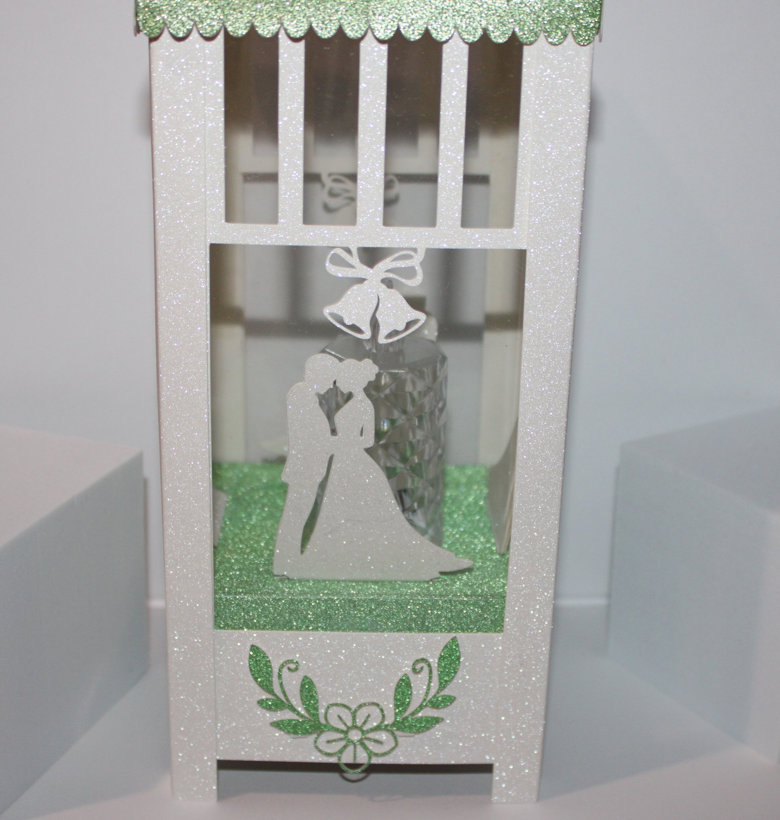 The base is elevated, featuring four silhouettes of the wedding couple. 