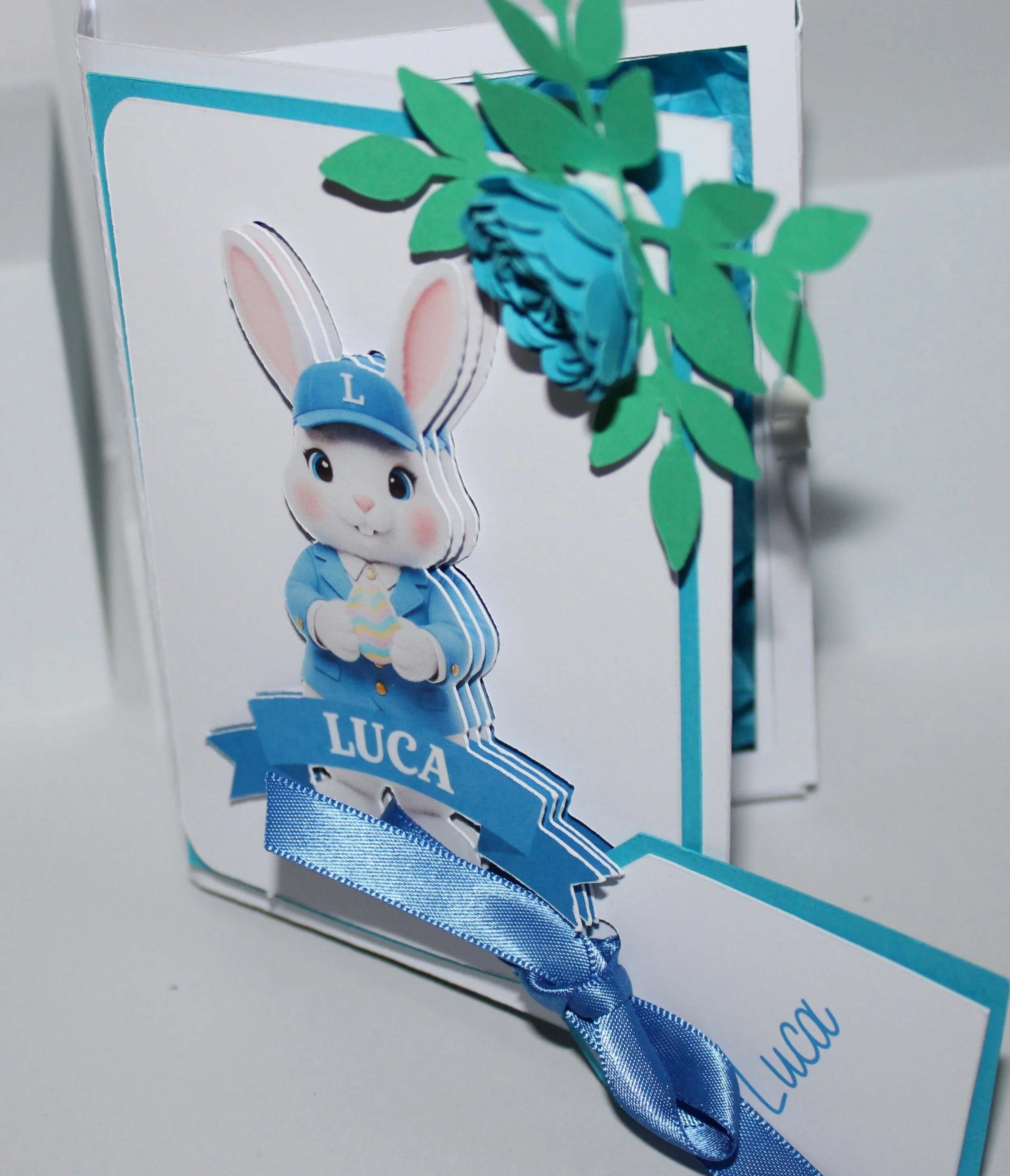 A personalised gift tag is attached for your message. Open the box to reveal a tissue-paper-lined interior, thoughtfully arranged and filled with mini chocolate eggs. The spine is inscribed with "Happy Easter" alongside the recipient’s name, creating