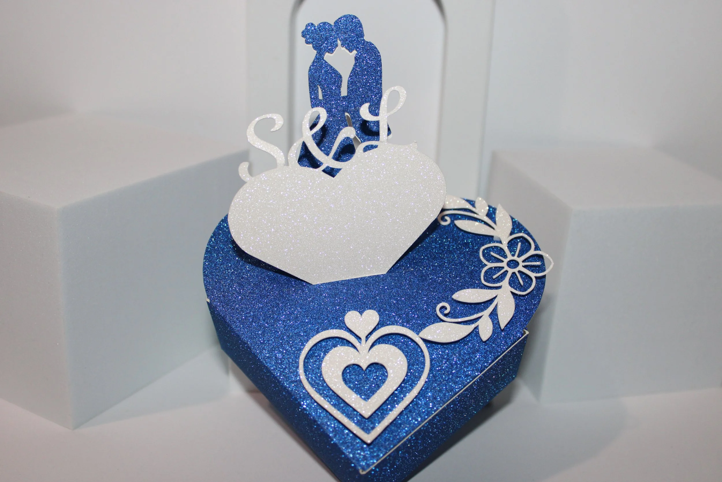 Heart shaped box with bride & groom plus heart with initials! 
This favour box has a gorgeous silhouette of A bride & groom attached to the box. 

In addition to this there is also a heart with your initials cutely placed on the top, making these uni