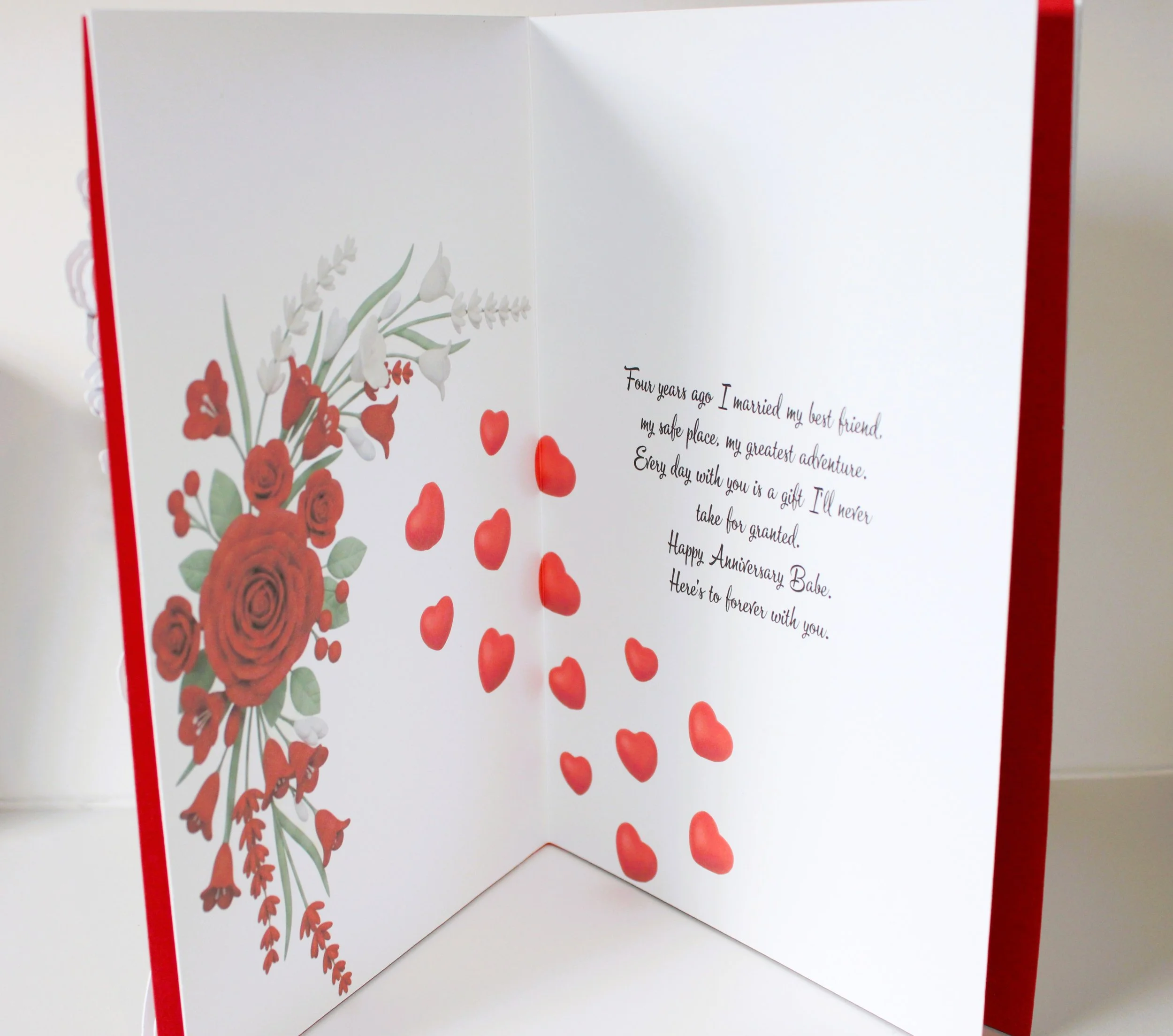 Inside (left panel) Red floral print along the inner margins, echoing the front’s palette and flowing gently toward the centre. Love hearts compliment the centre of the card. Message inside reads: Four years ago I married my best friend, my safe plac