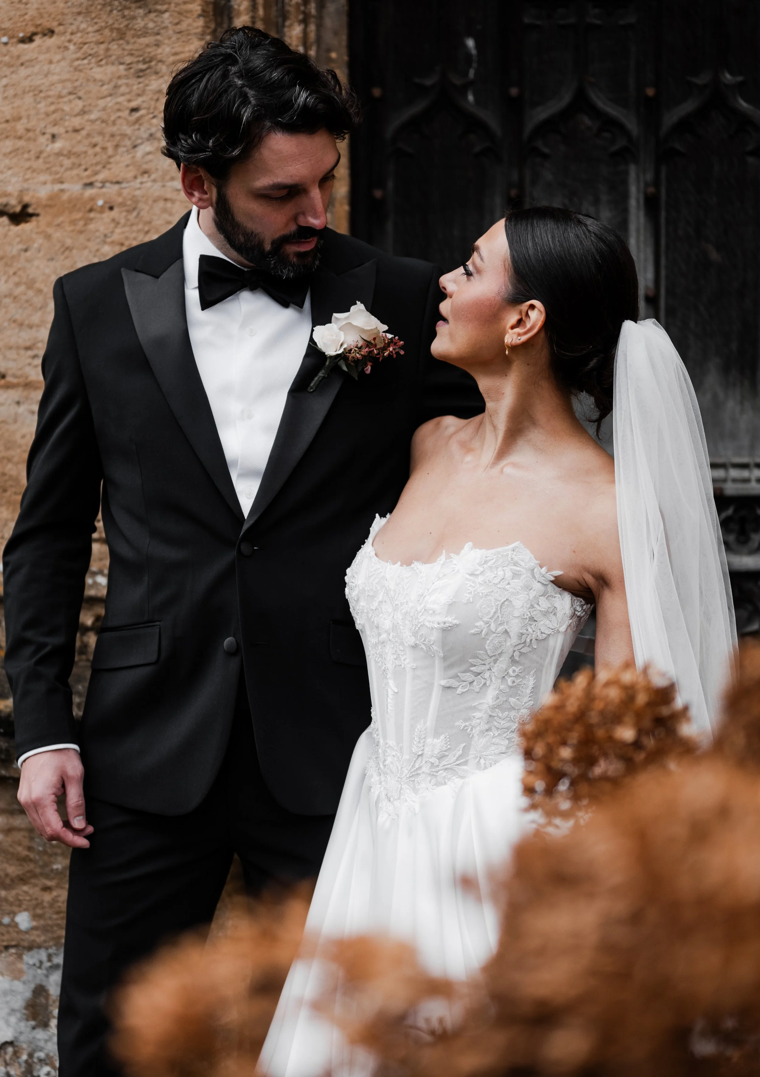 A bride and groom in wedding attire standing close together and looking into each other's eyes outdoors at sudeley castle, Gareth roy photography
