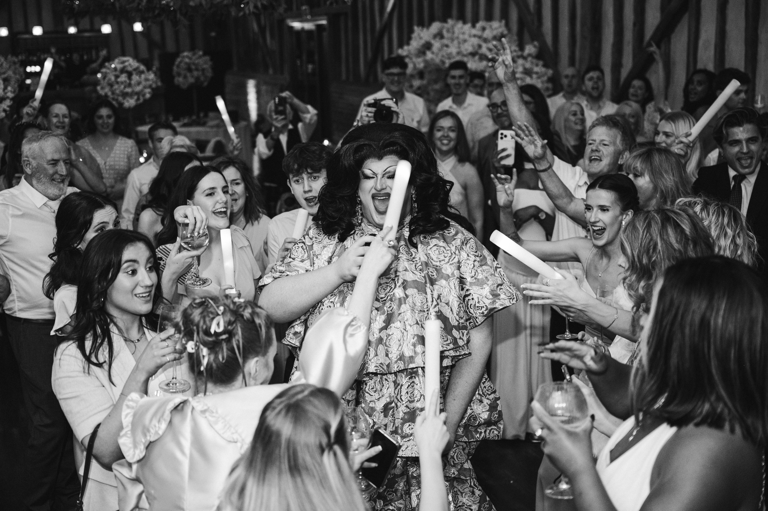 People celebrating and singing along while a drag queen is singing in the middle