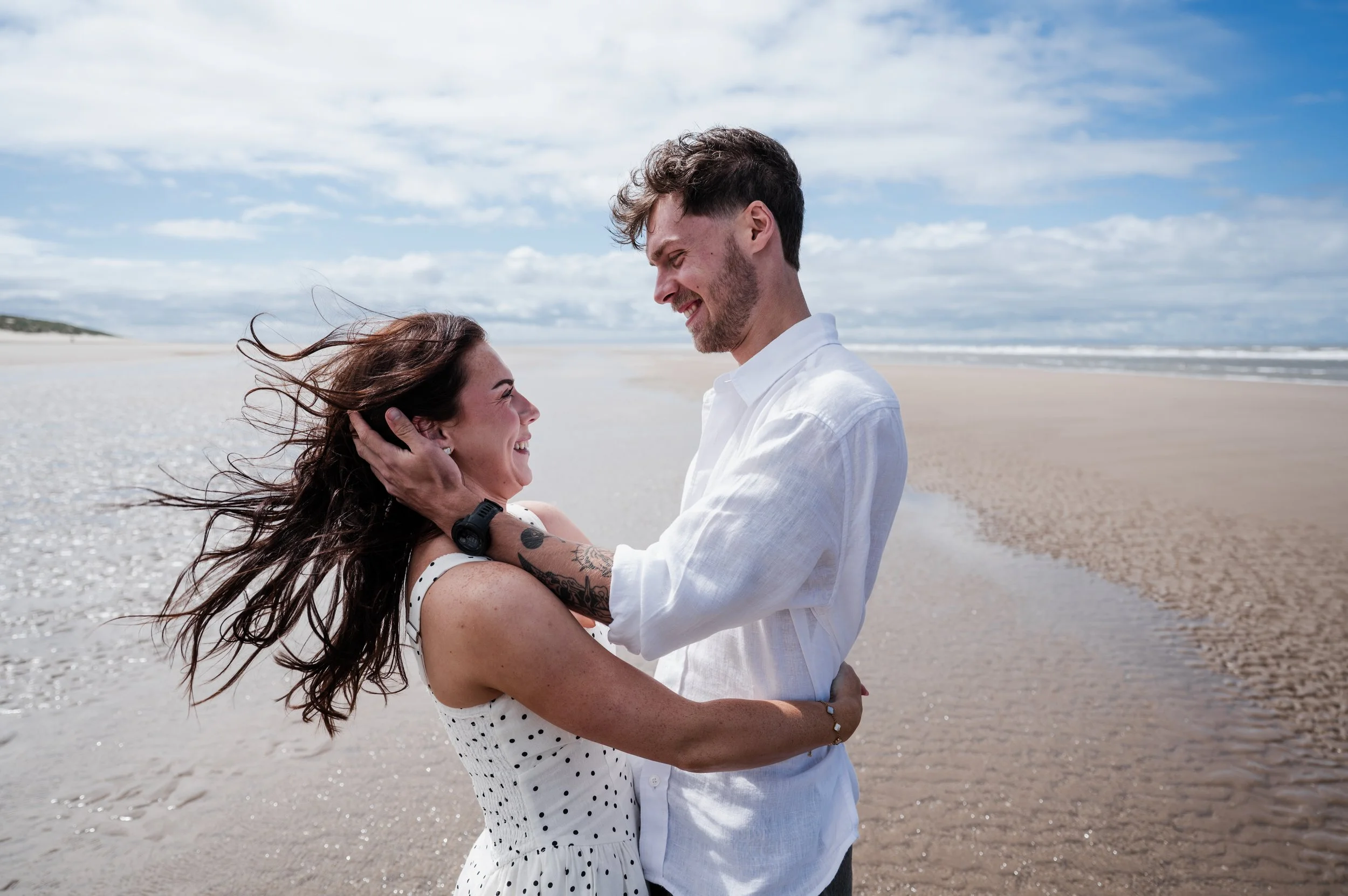Image of man and woman on a beach in an embrace and smiing at each other