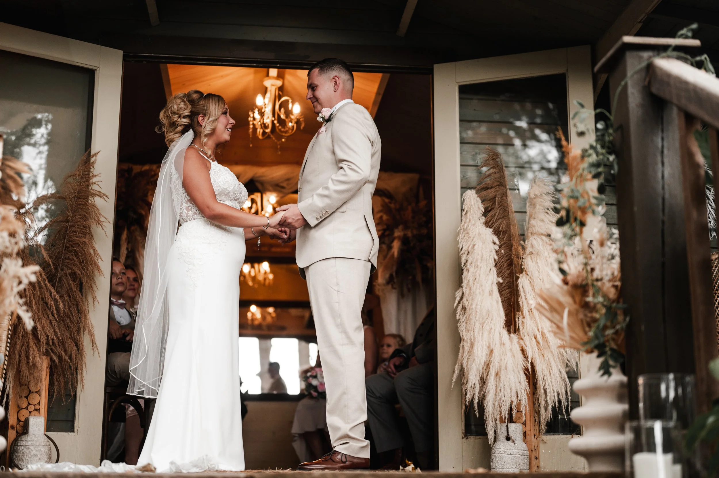 The Love Shack - Groom and bride in wedding attire, facing each other and holding hands during a ceremony.