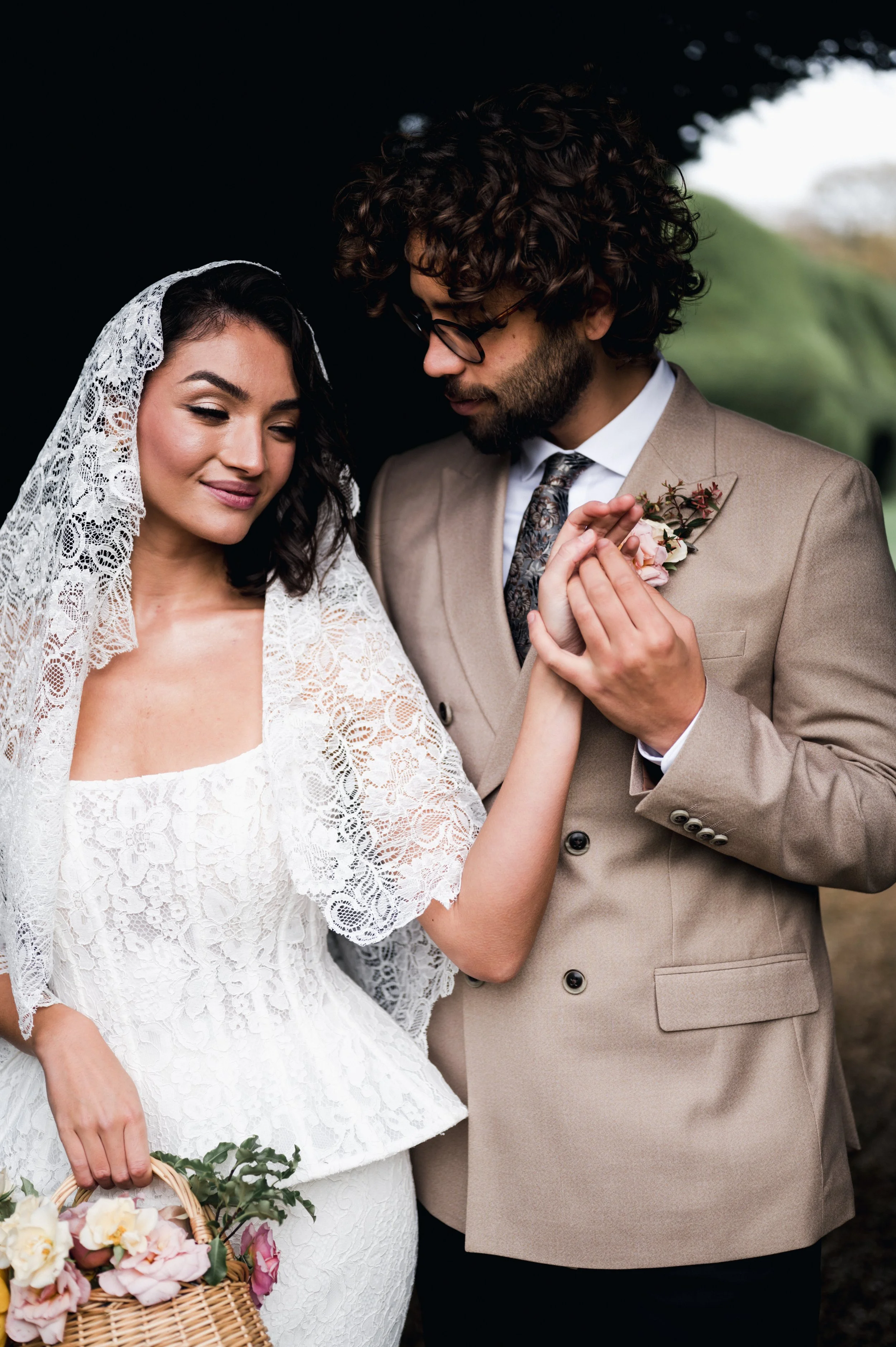 A bride and groom holding hands, dressed in wedding attire, sharing a tender moment outdoors at sudeley castle, Gareth roy photography