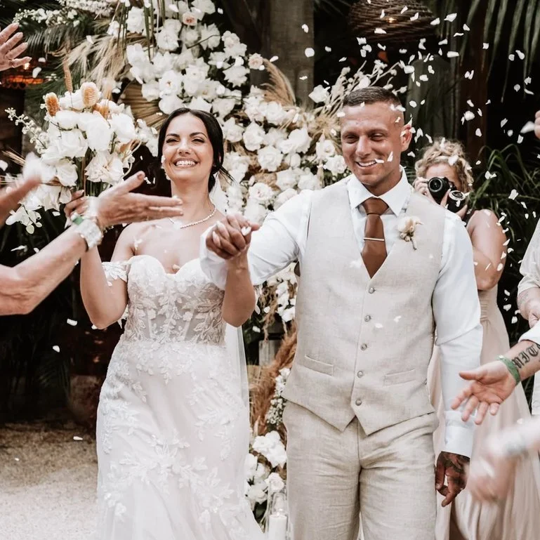 Image of bride and groom in wedding attire, walking down the aisle and confetti falling on them