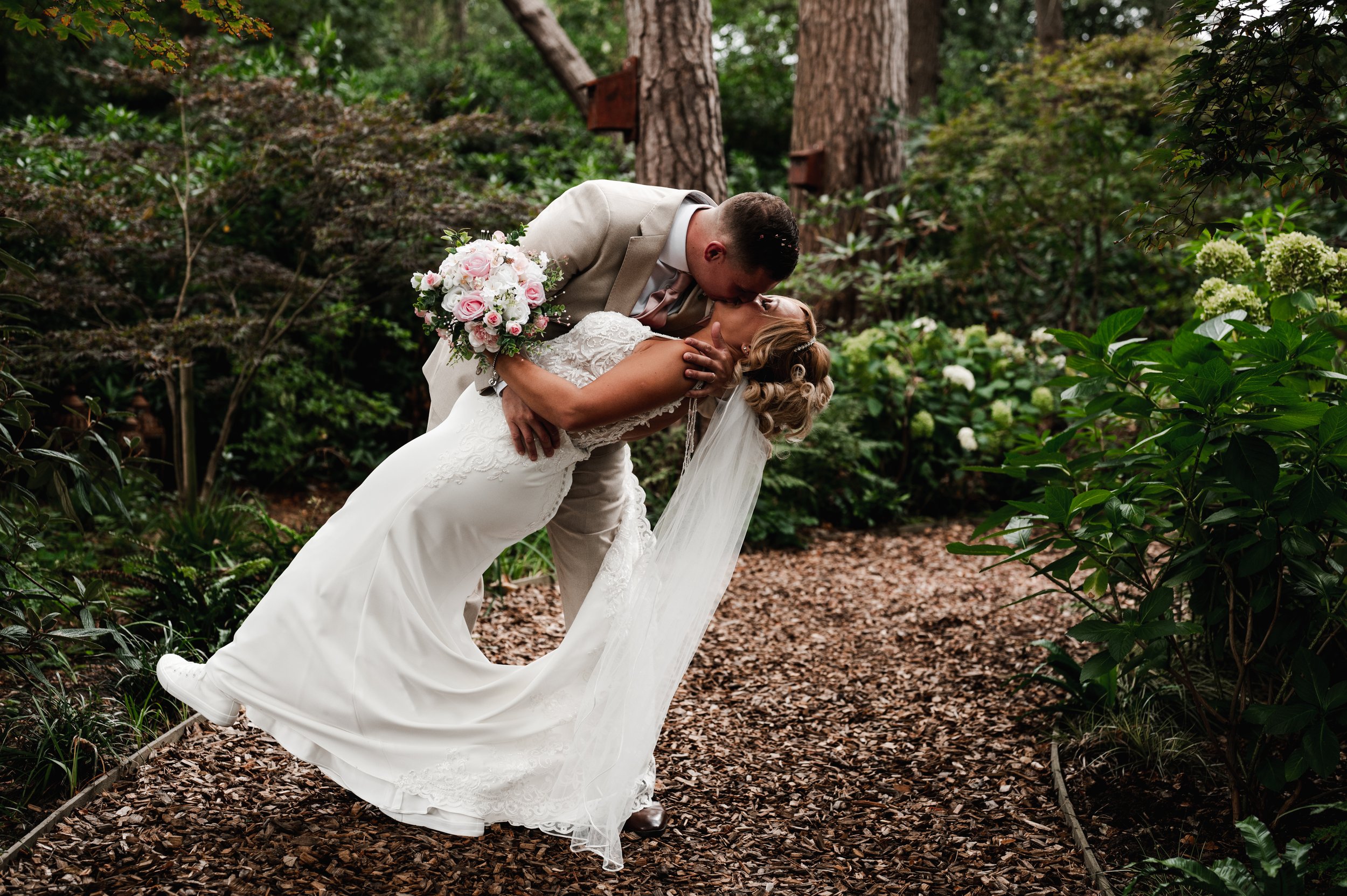 The Love Shack - Groom and bride stood in a forest while bride is being dipped for a kiss