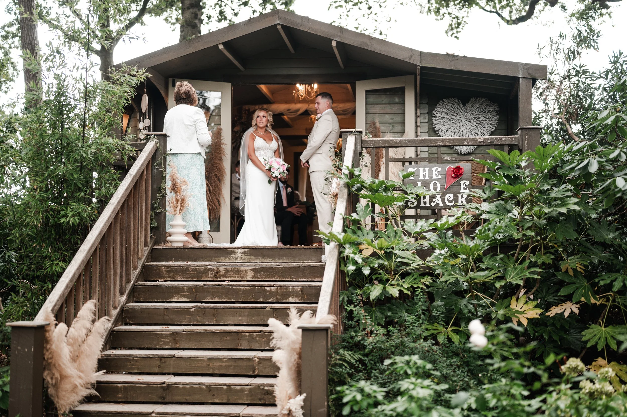 The Love Shack - Groom and bride in wedding attire during a ceremony on top of an outdoor wooden staircase