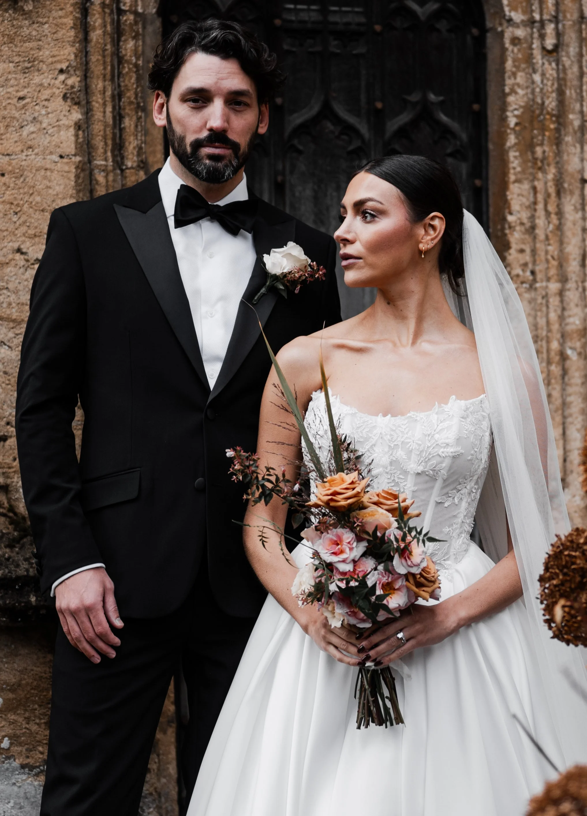 A bride and groom standing outdoors in front of a stone building. at sudeley castle, Gareth roy photography