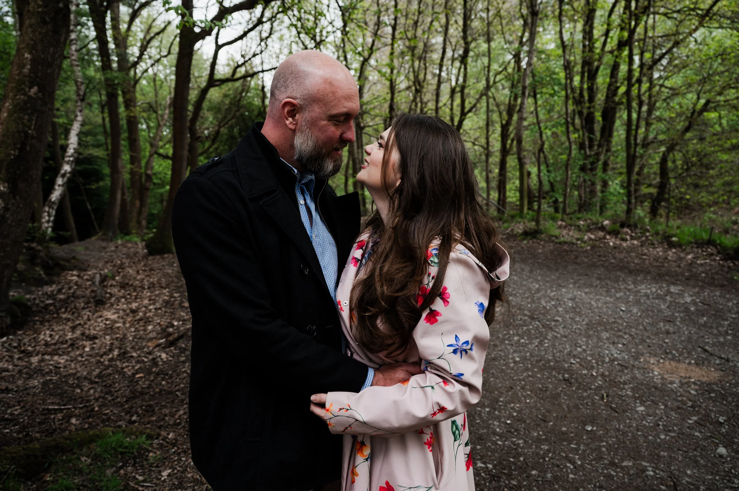 Delamere Forest Engagement shoot - man and woman embraced and and looking at each other with woodland behind them