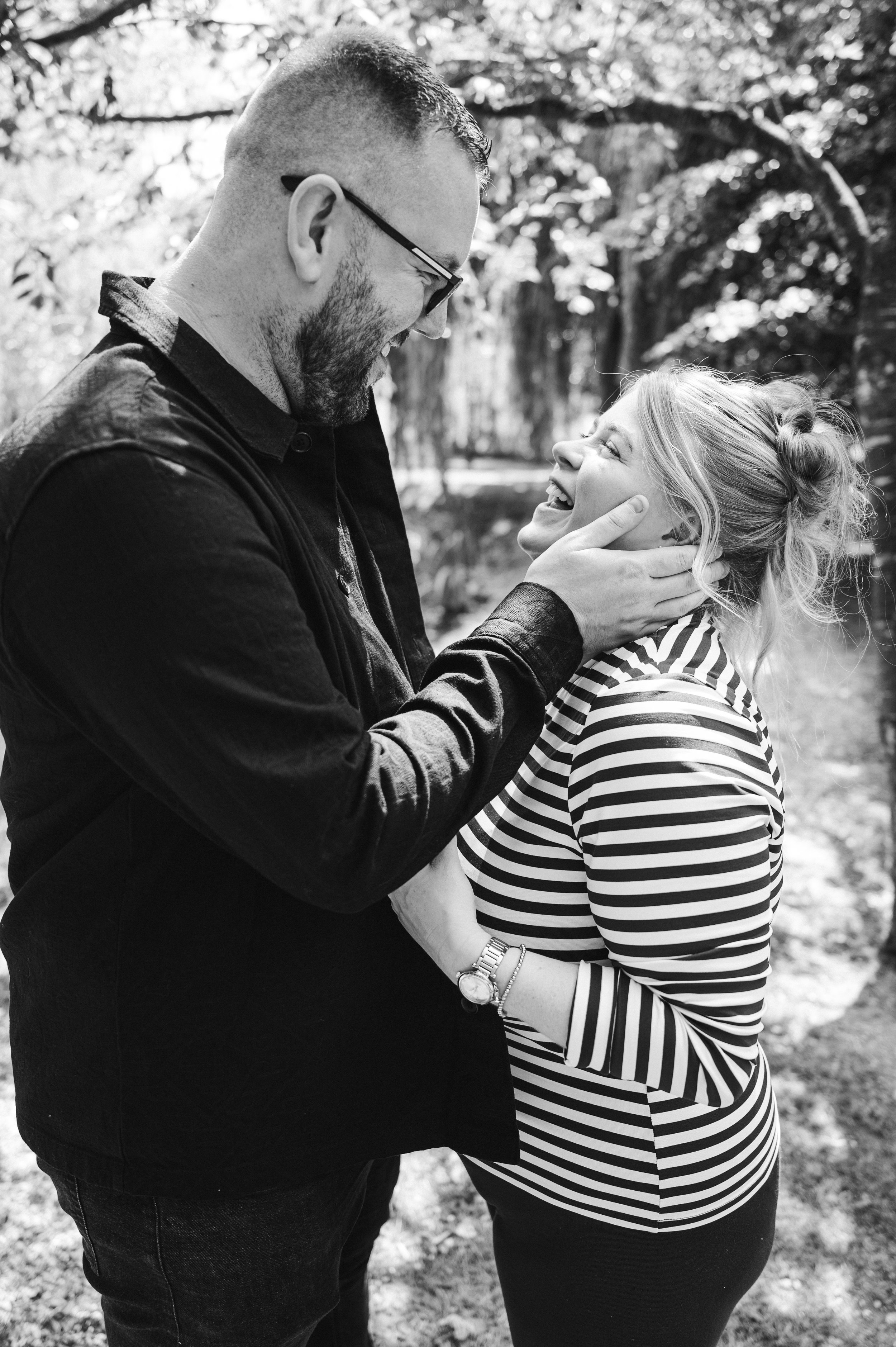 The Grosvenor Pulford Engagement - Black and white picture of man in black shirt and woman in striped top laughing while man holds womans face