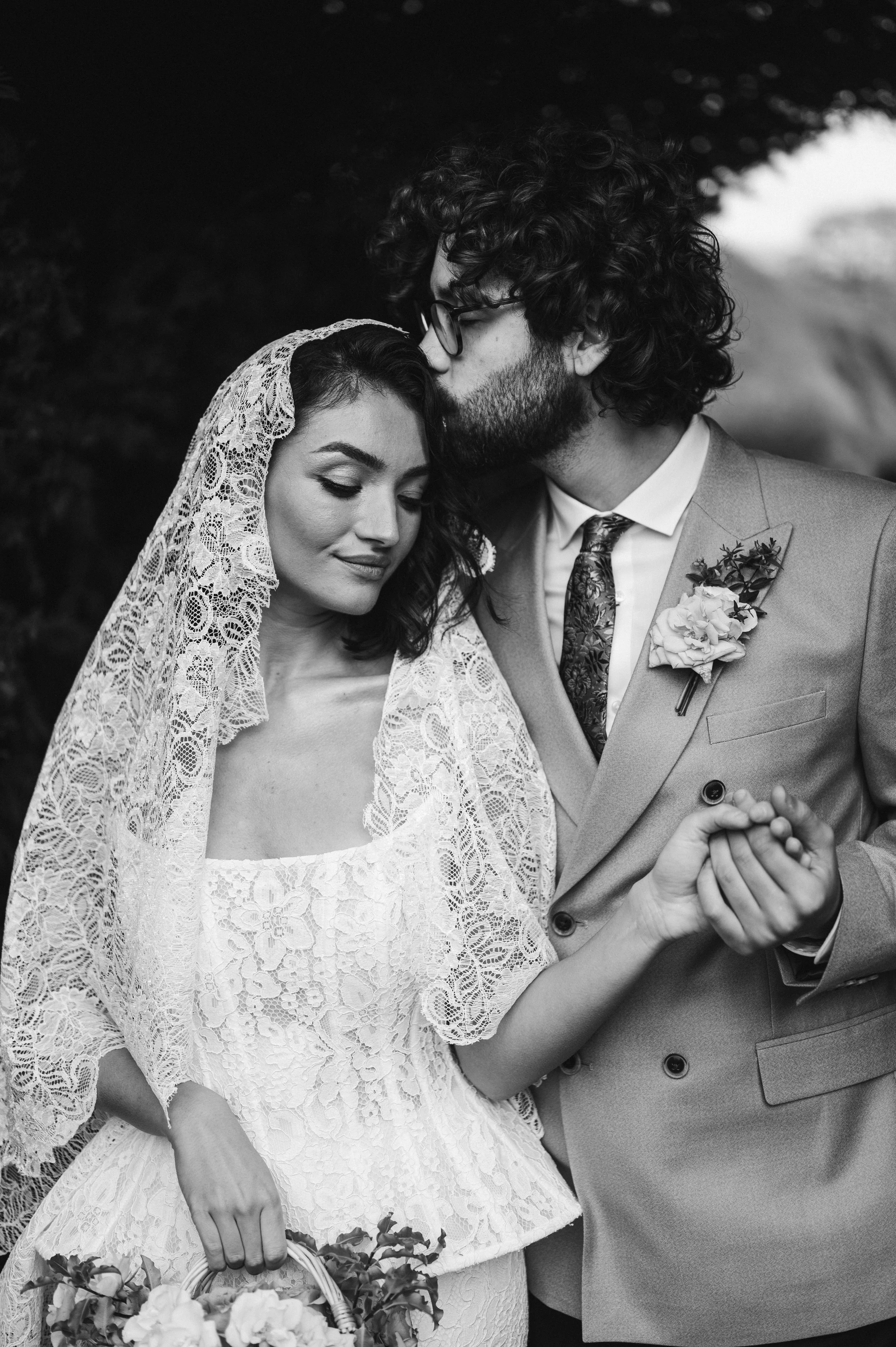 A black and white photo of a bride and groom on their wedding day. The bride is wearing a lace dress and a lace veil, holding a bouquet at sudeley castle, Gareth roy photography