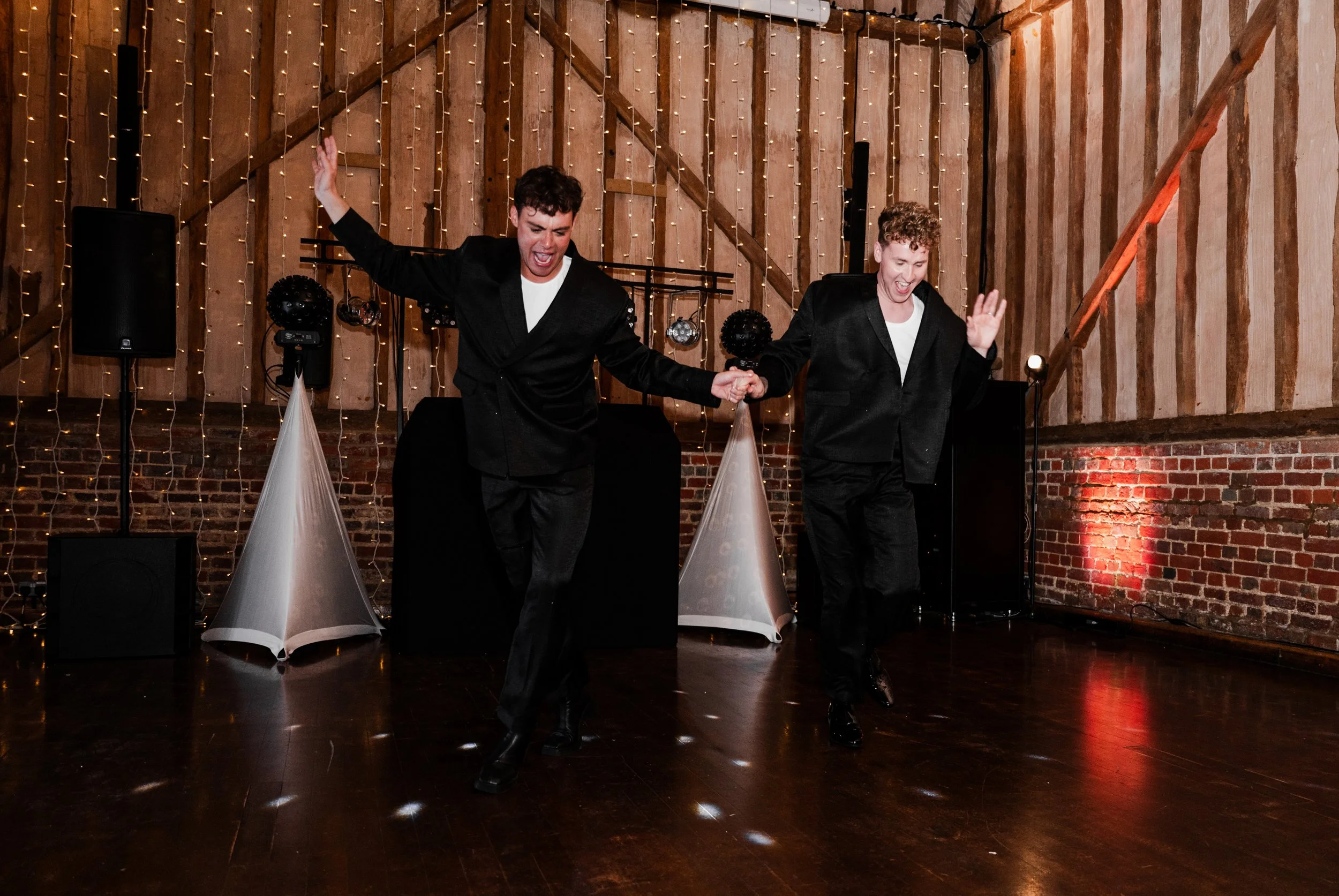Two grooms, dressed in black and dancing together