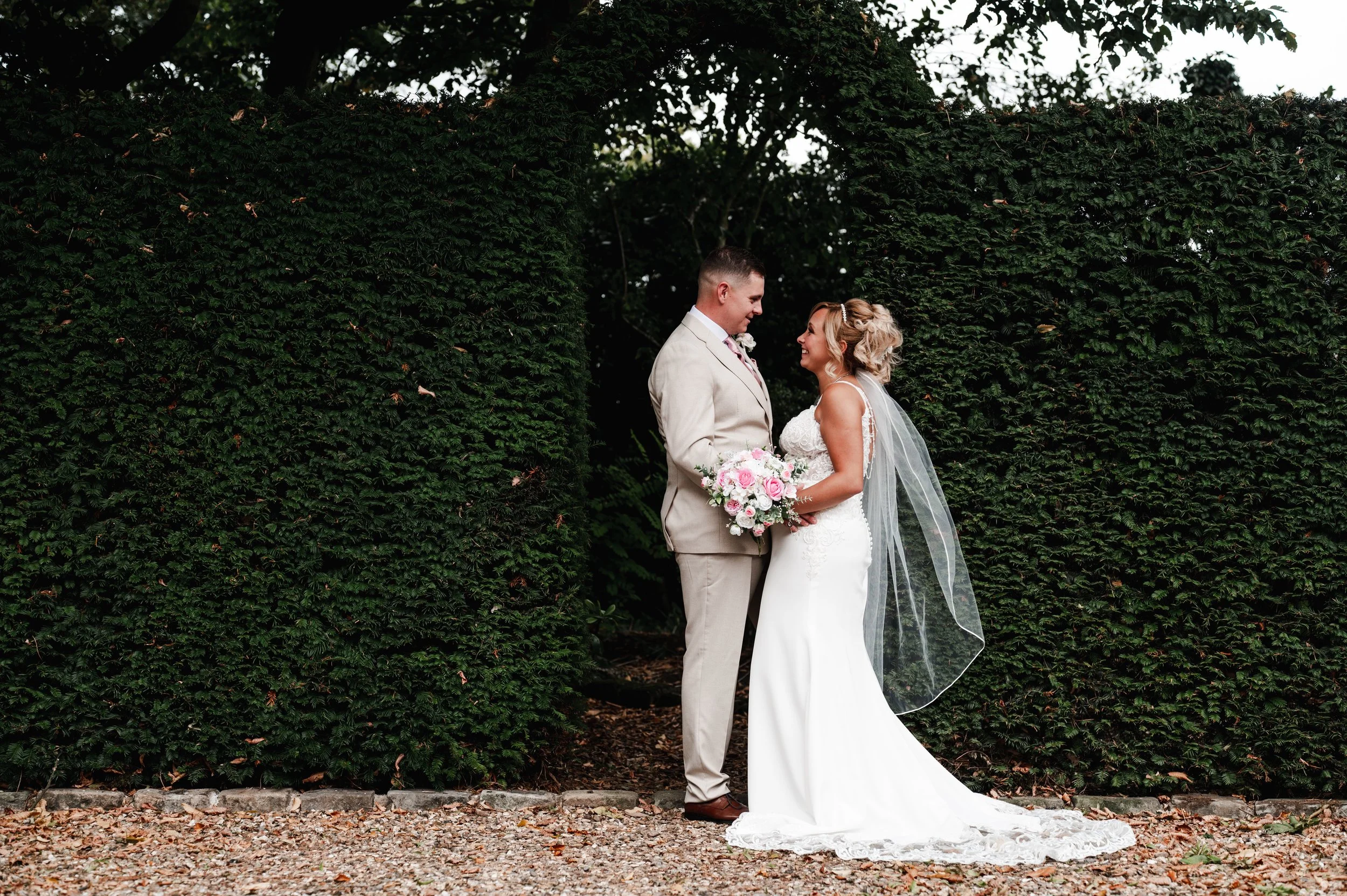 The Love Shack - groom and bride in wedding attire, stood in front a arch made of leaves