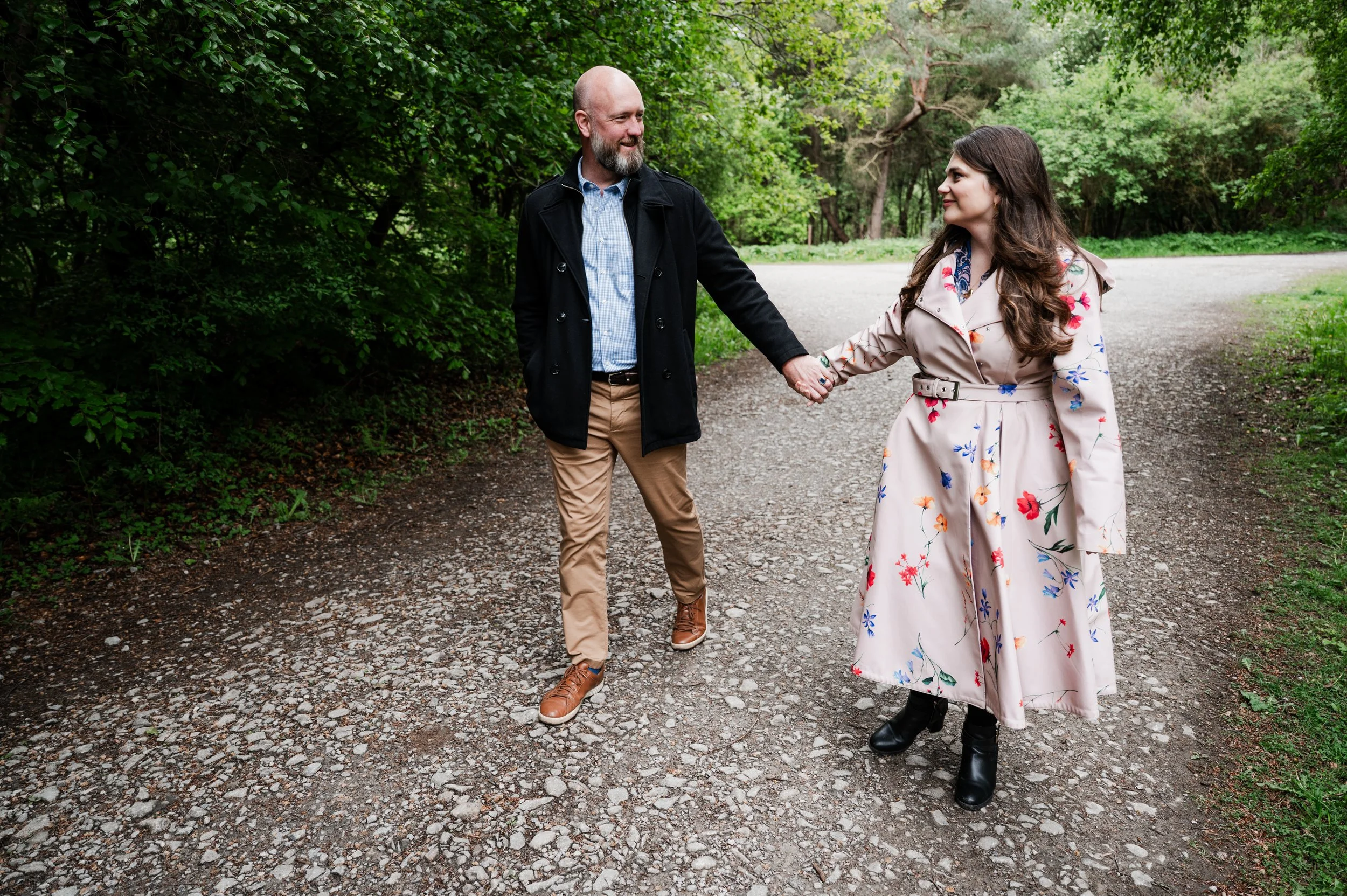 Delamere Forest Engagement shoot - man and woman holding hands and smiling at each other and walking along a path