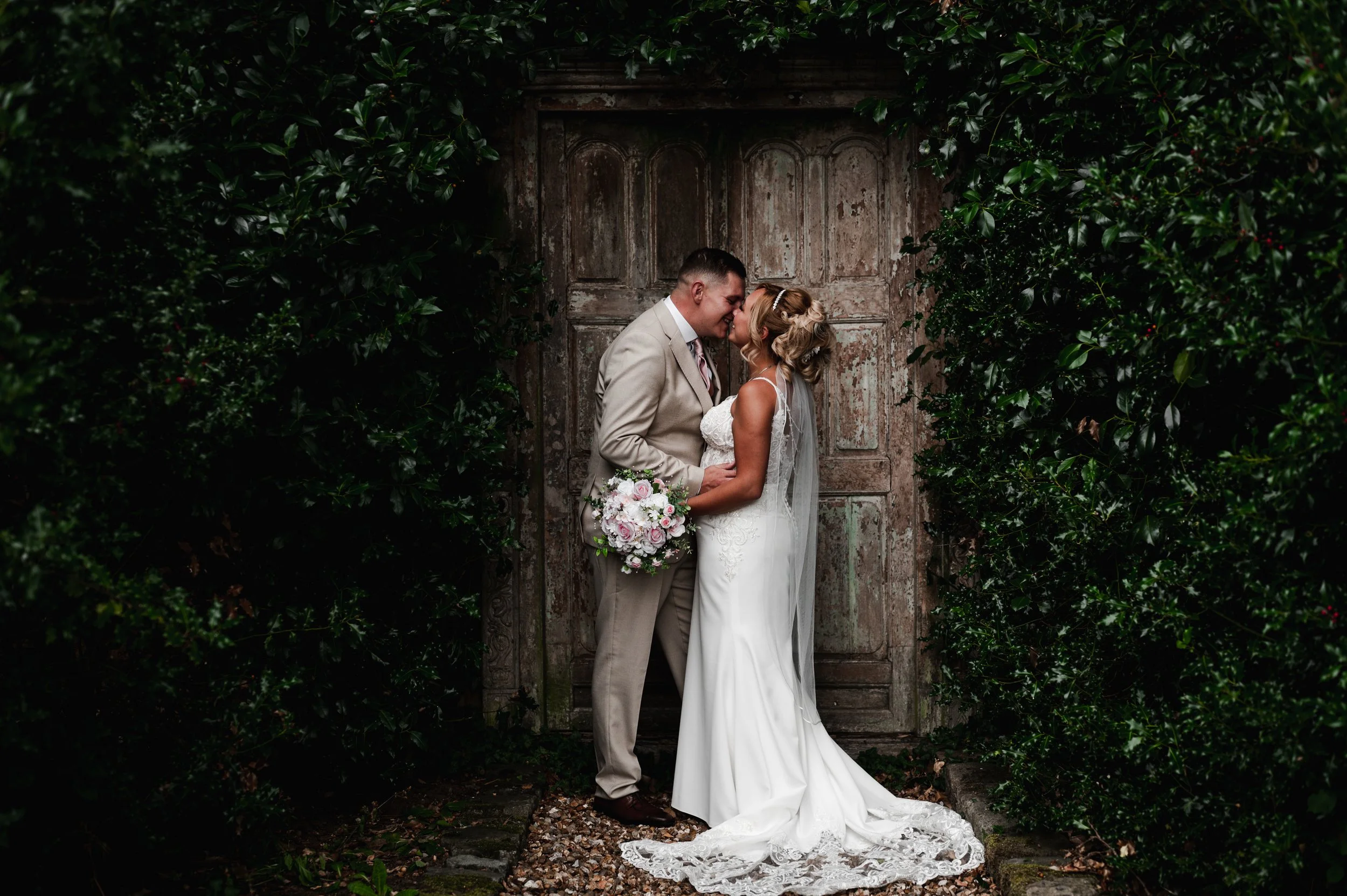 The Love Shack - Groom and bride in wedding attire, looking at each other in front of an old wooden door. 