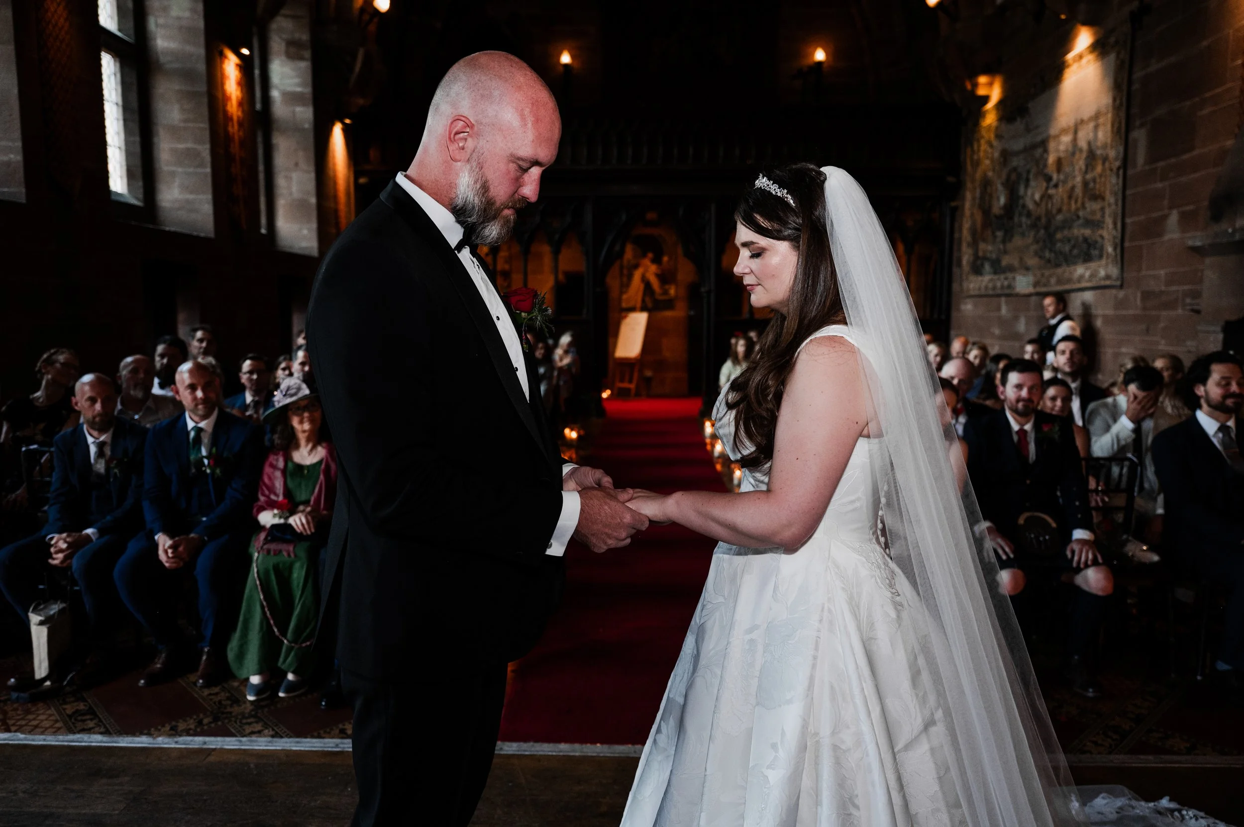 Peckforton Castle - bride and groom in wedding attire exchanging wedding rings