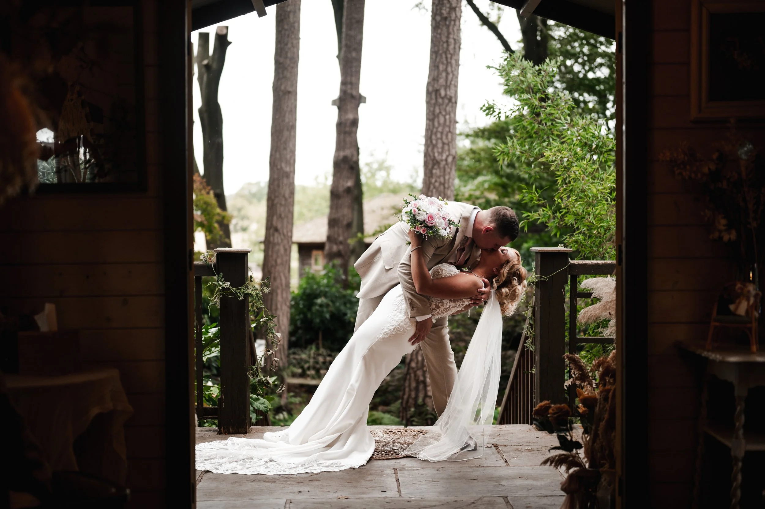 The Love Shack - Groom and bride in wedding attire with the bride being dipped for a kiss on top of a wooden staircase. 