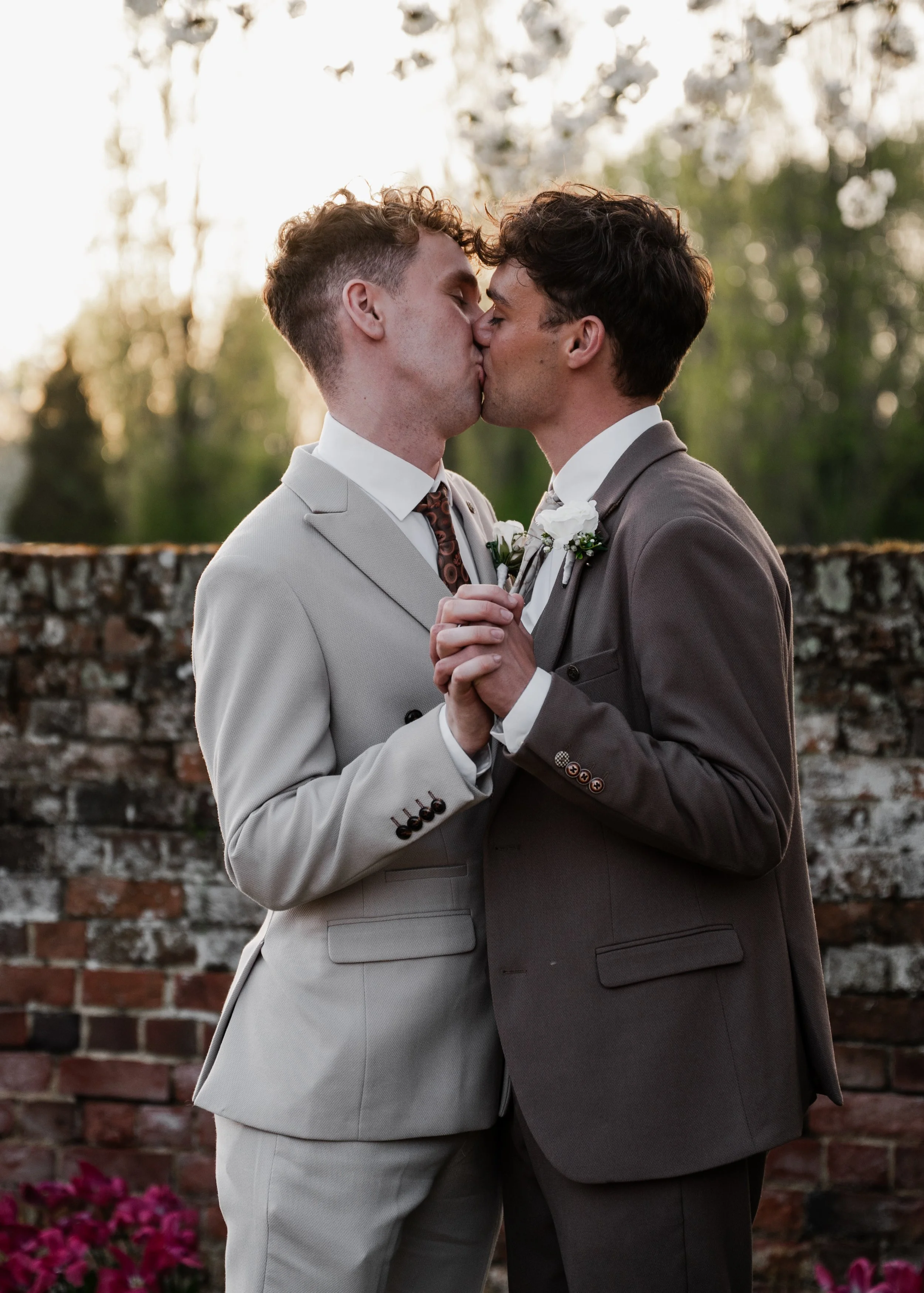 Two grooms in wedding attire kissing after their wedding