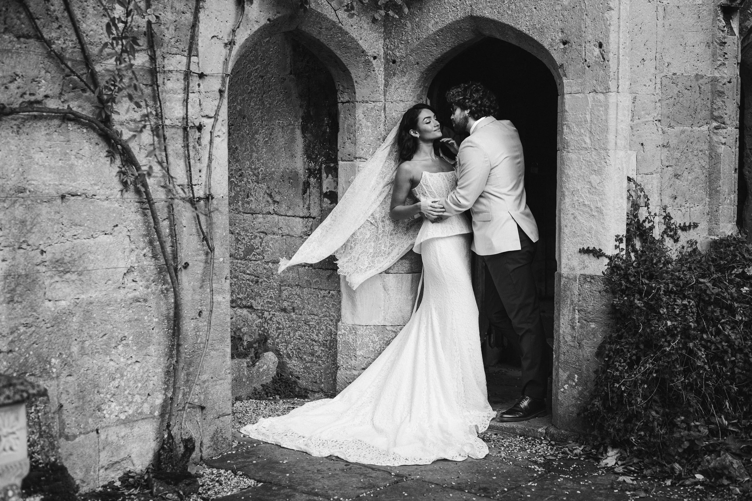 Black and white photo of a bride and groom standing close in an old stone doorway at sudeley castle, Gareth roy photography