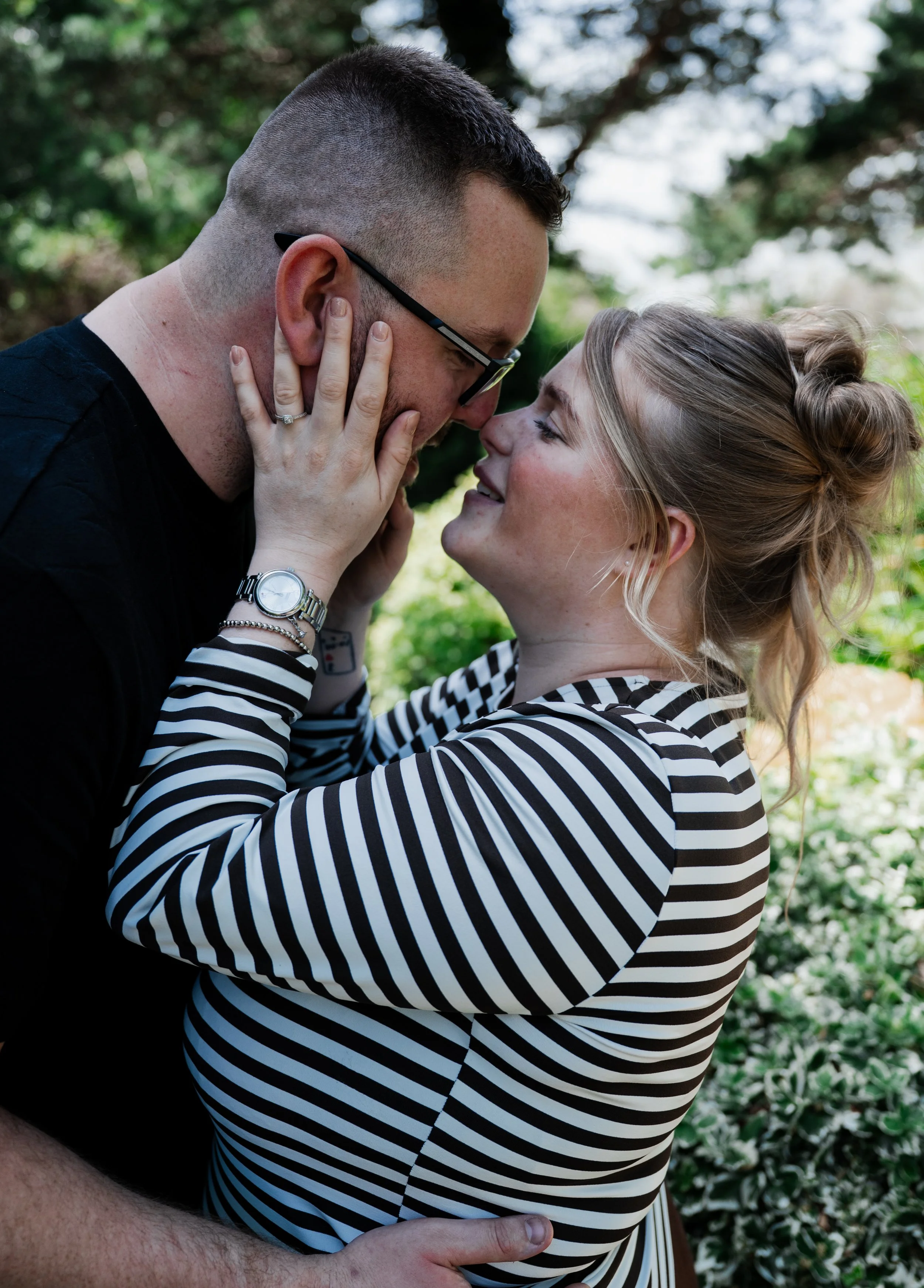 The Grosvenor Pulford Engagement - man in black shirt and woman in striped top, embracing and about to kiss