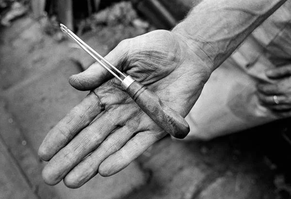 Cotton weavers hand holding an old tool called a drawing hook