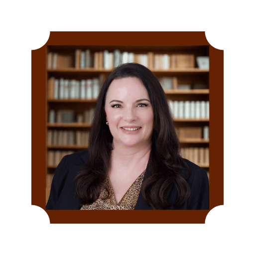 A woman with long dark hair smiling in front of a bookshelf filled with books.