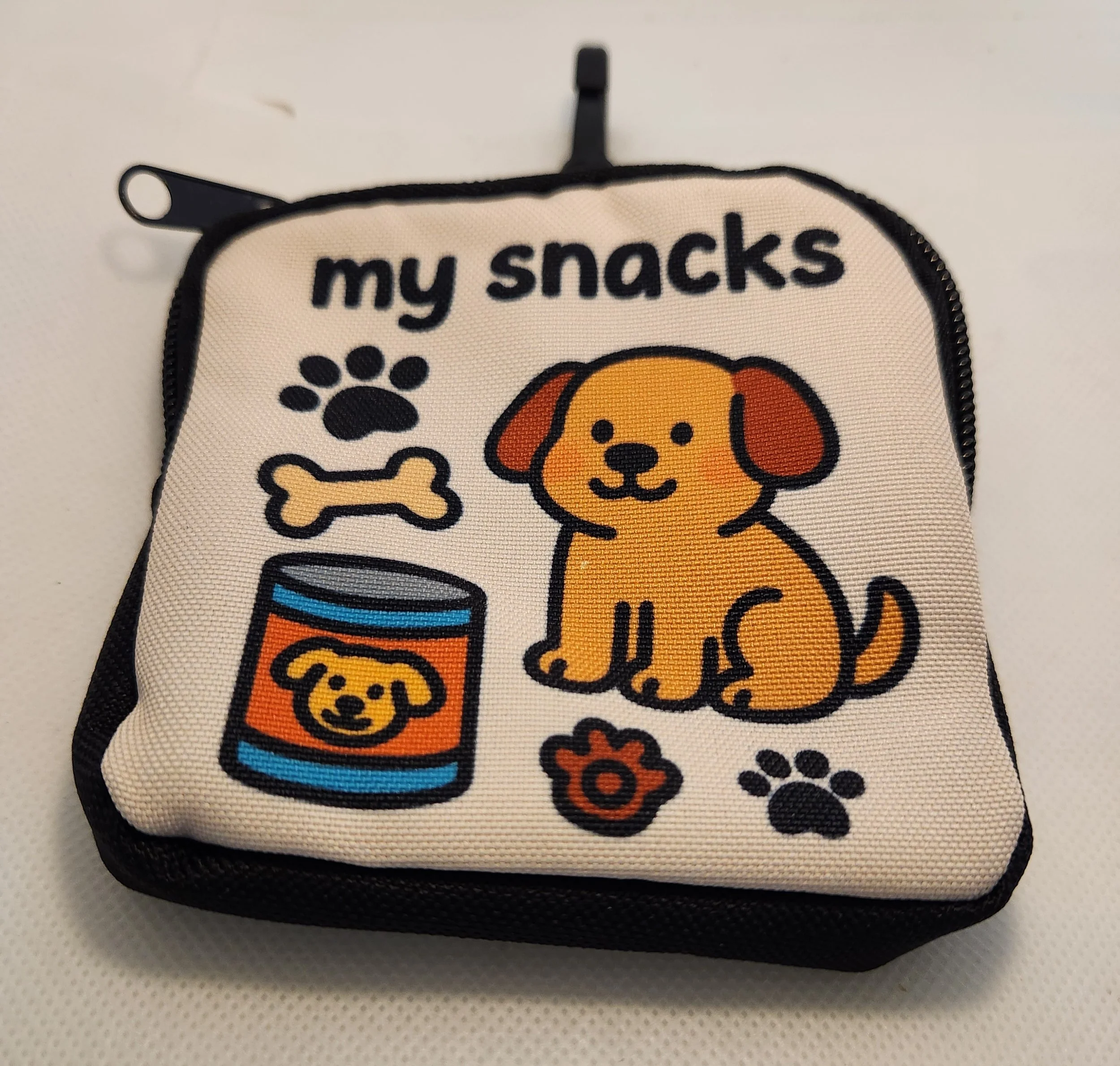 Small fabric snack pouch with cartoon dog theme, featuring a dog illustration, a paw print, a bone, a food can with dog face, and a small flower design.
