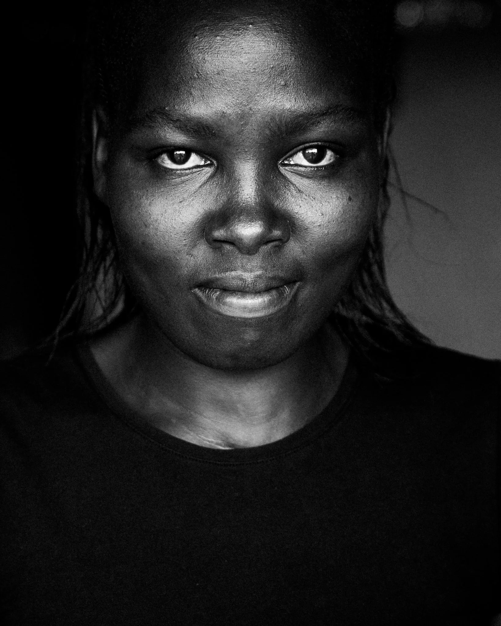 Close-up black and white portrait of a woman with wet hair, looking directly at the camera with a confident expression.