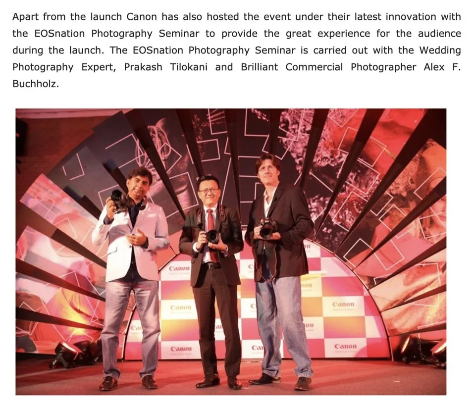 Three men standing on a stage with a colorful background and holding cameras