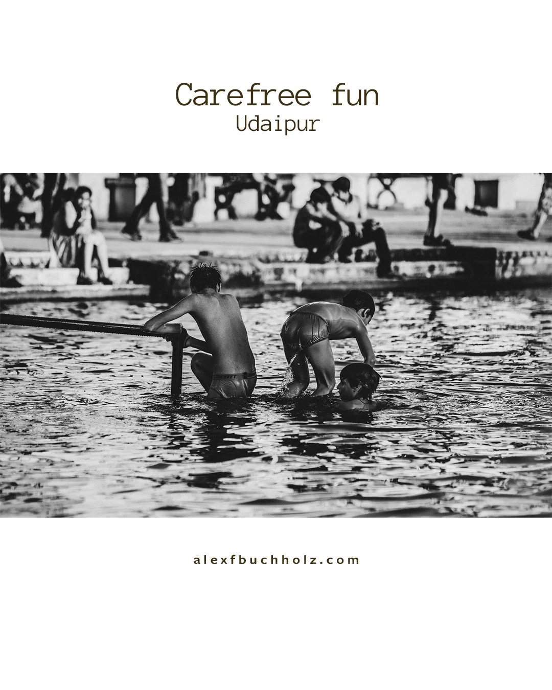 Children playing in a river, with some sitting on the bank and others in the water, during daytime.