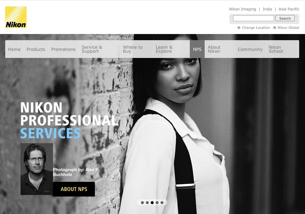 Black and white photograph of a woman leaning against a brick wall, looking at the camera. The webpage header shows a Nikon logo and menu options. Text on the page reads 'Nikon Professional Services' with a smaller photo of a man labeled 'Photograph 