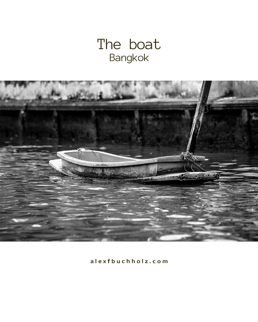 A black and white photo of an old, small, wooden boat floating on water in Bangkok