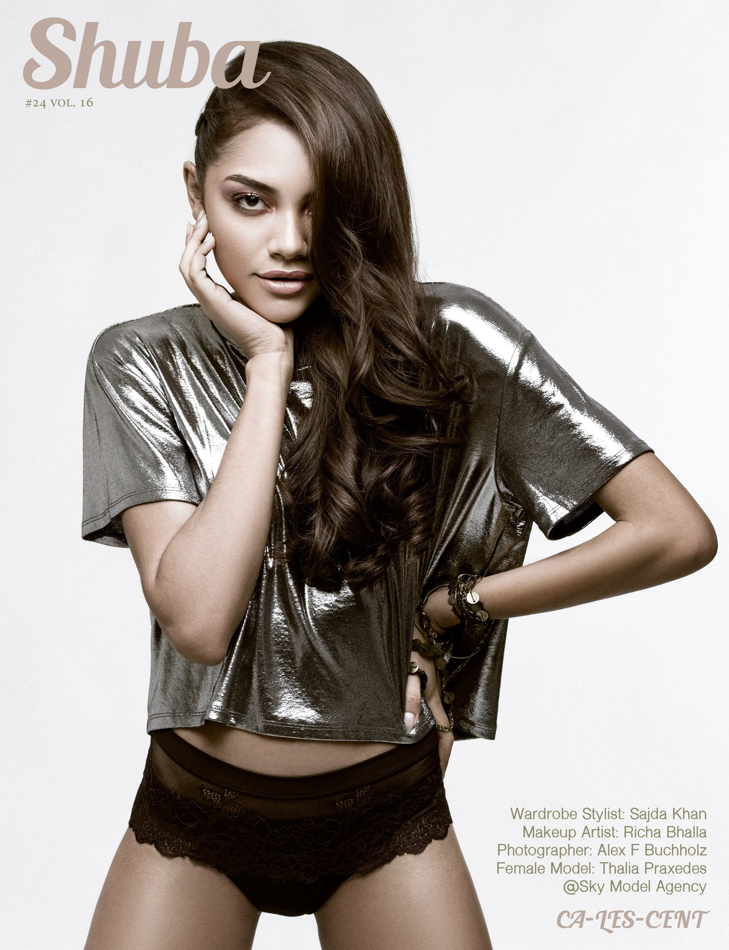 Magazine cover featuring a woman with long brown hair, wearing a shiny metallic top and black lace underwear, posing with one hand on her face and the other on her hip.