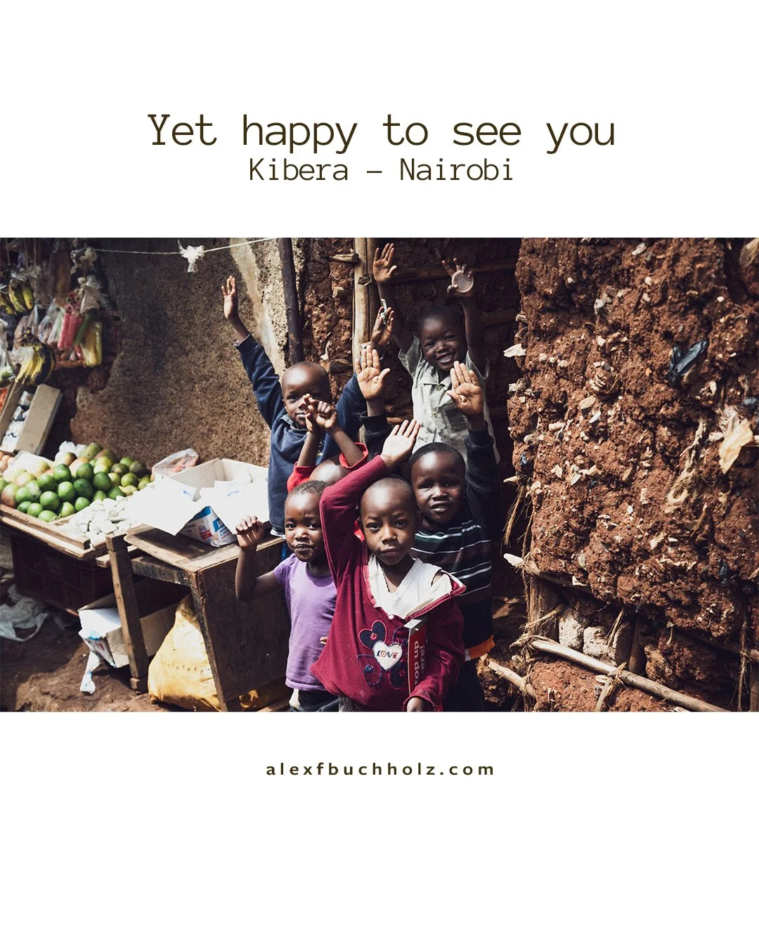 Group of children smiling and waving at a marketplace with fruit stands in Kibera, Nairobi.