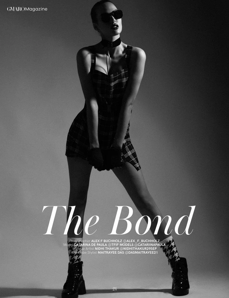 Black and white fashion photo of a woman with short hair and sunglasses, wearing a plaid dress, gloves, and boots, standing with legs apart and hands in front, with the text "The Bond" and credits for photographer, model, makeup artist, wardrobe styl