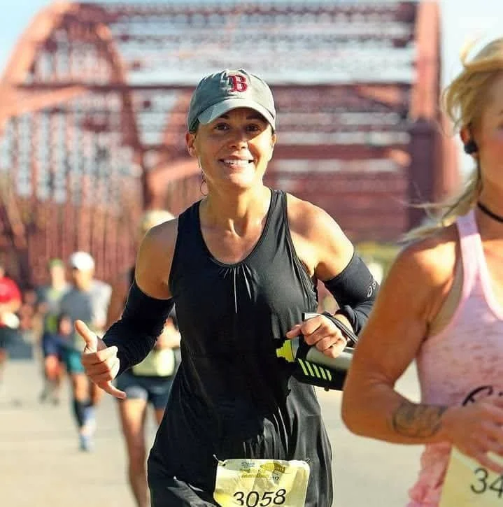 Woman wearing a Boston Red Sox hat and black tank top runs a marathon