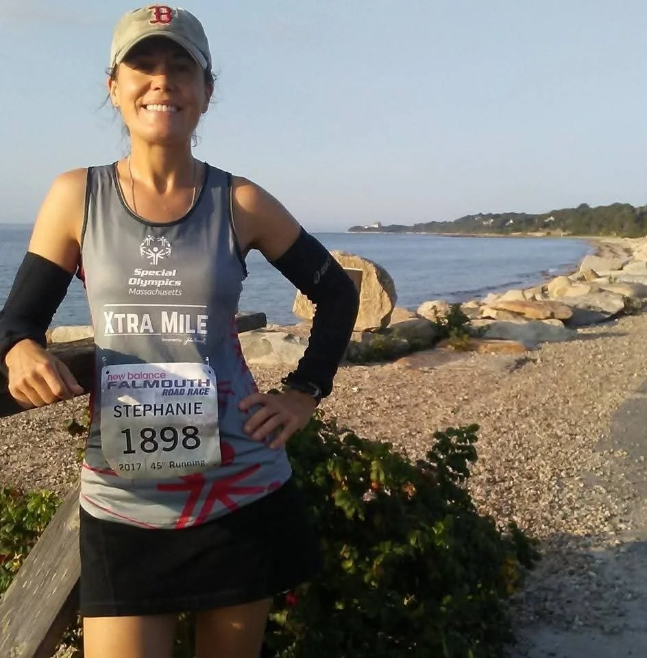 Woman wearing a Boston Red Sox hat and a Special Olympics running tank top and race bib poses for a photo