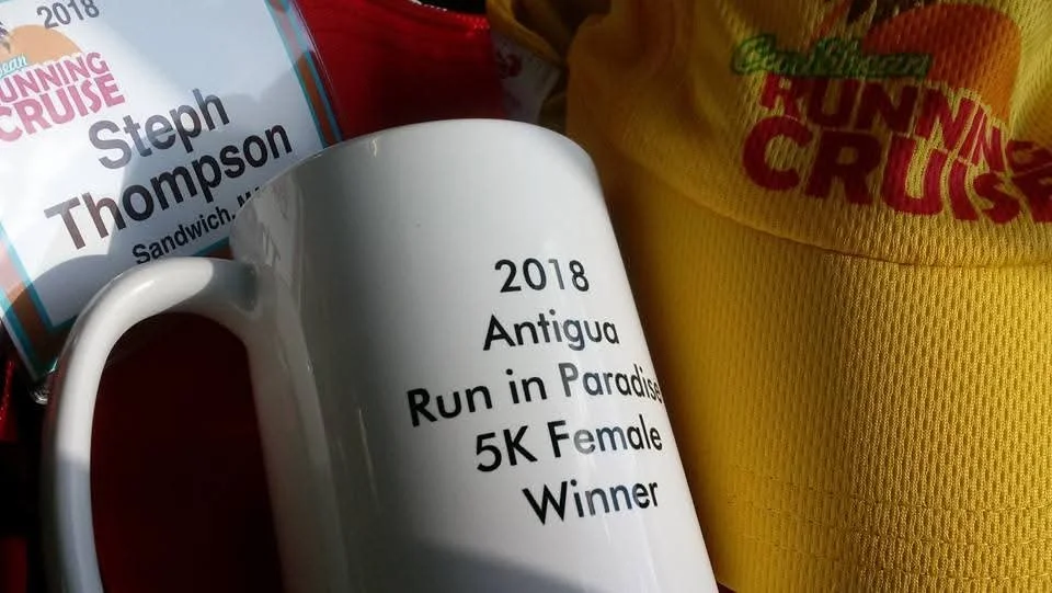 Mug that says 2018 Antigua Ruin in Paradise 5K Female Winner next to a Running Cruise yellow hat