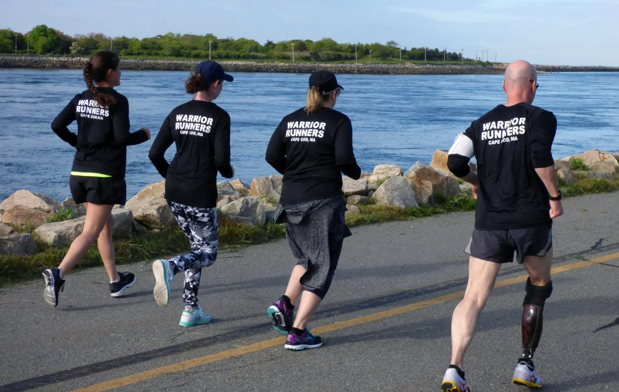 Group of four people wearing Warrior Runners shirts run together
