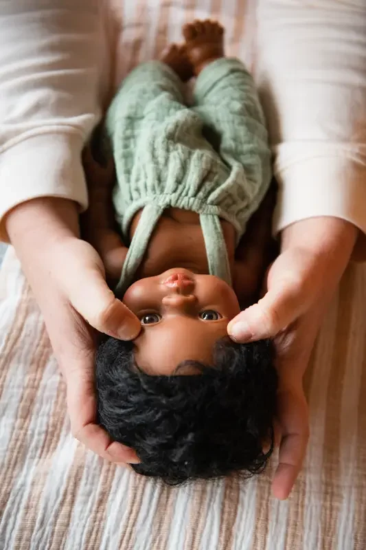 Démonstration d'un massage bébé à des parents sur une poupée.