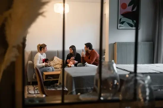 Une infirmière lors d'un échange avec un couple et leur nouveau né répondant à toute leurs questions sur la parentalité et le post-partum.