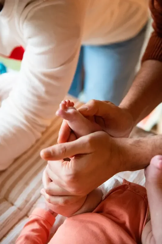 Une personne tenant doucement le pied d'un bébé lors d'un massage.