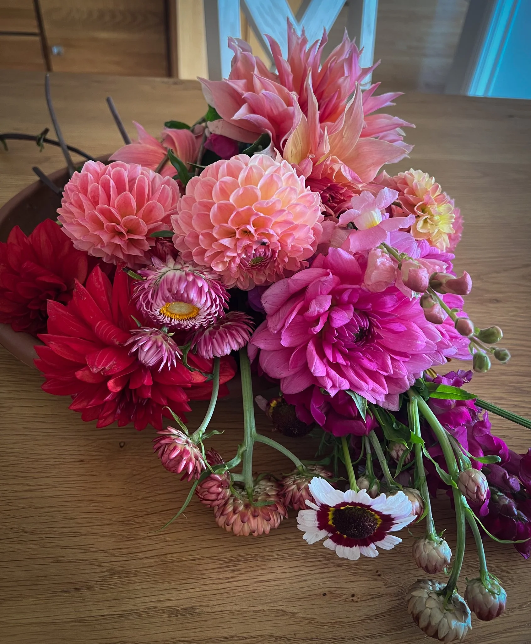 A colorful bouquet of various pink, red, and white flowers on a wooden table.