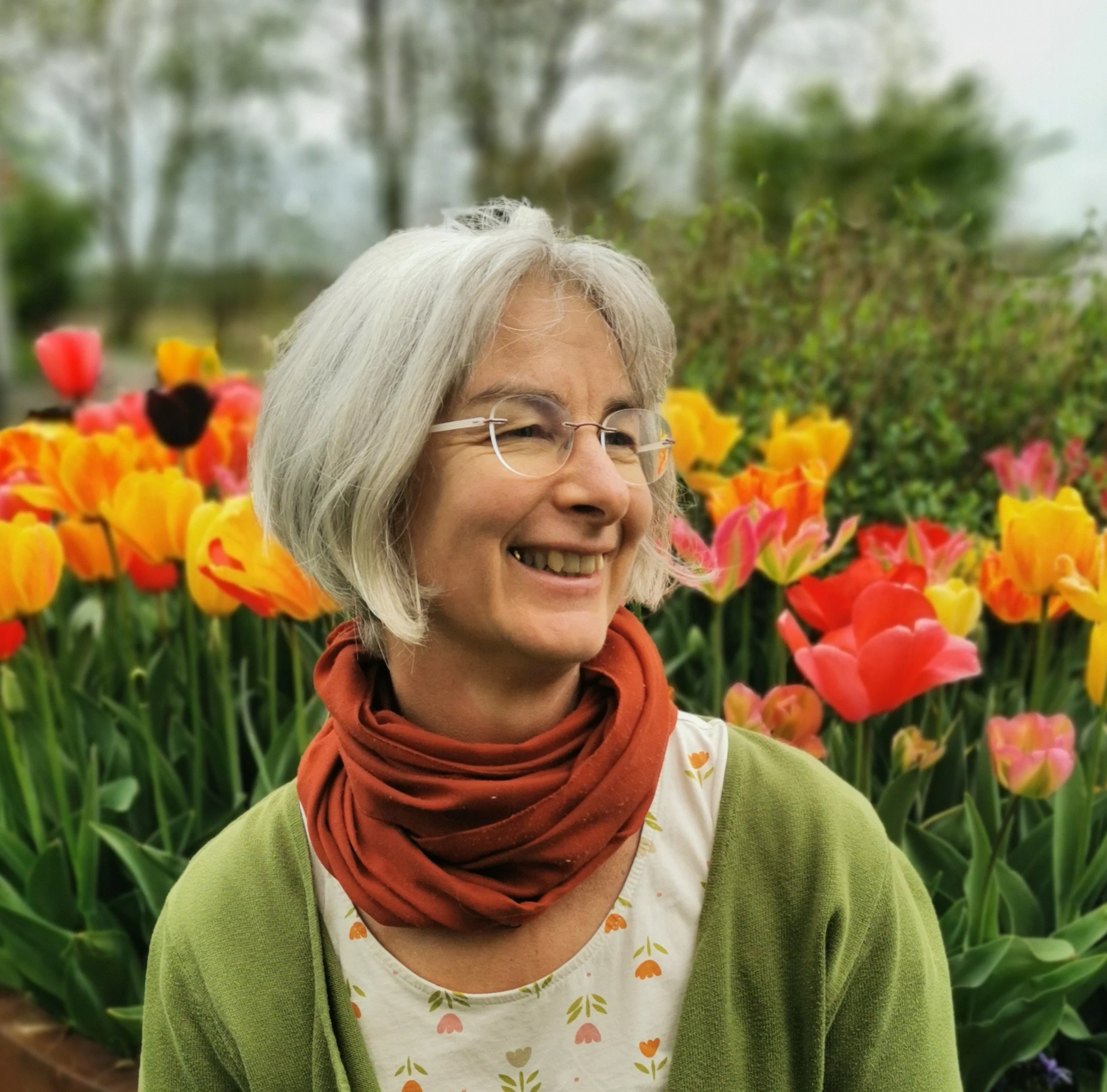 Lächelnde Frau vor bunten Tulpen.