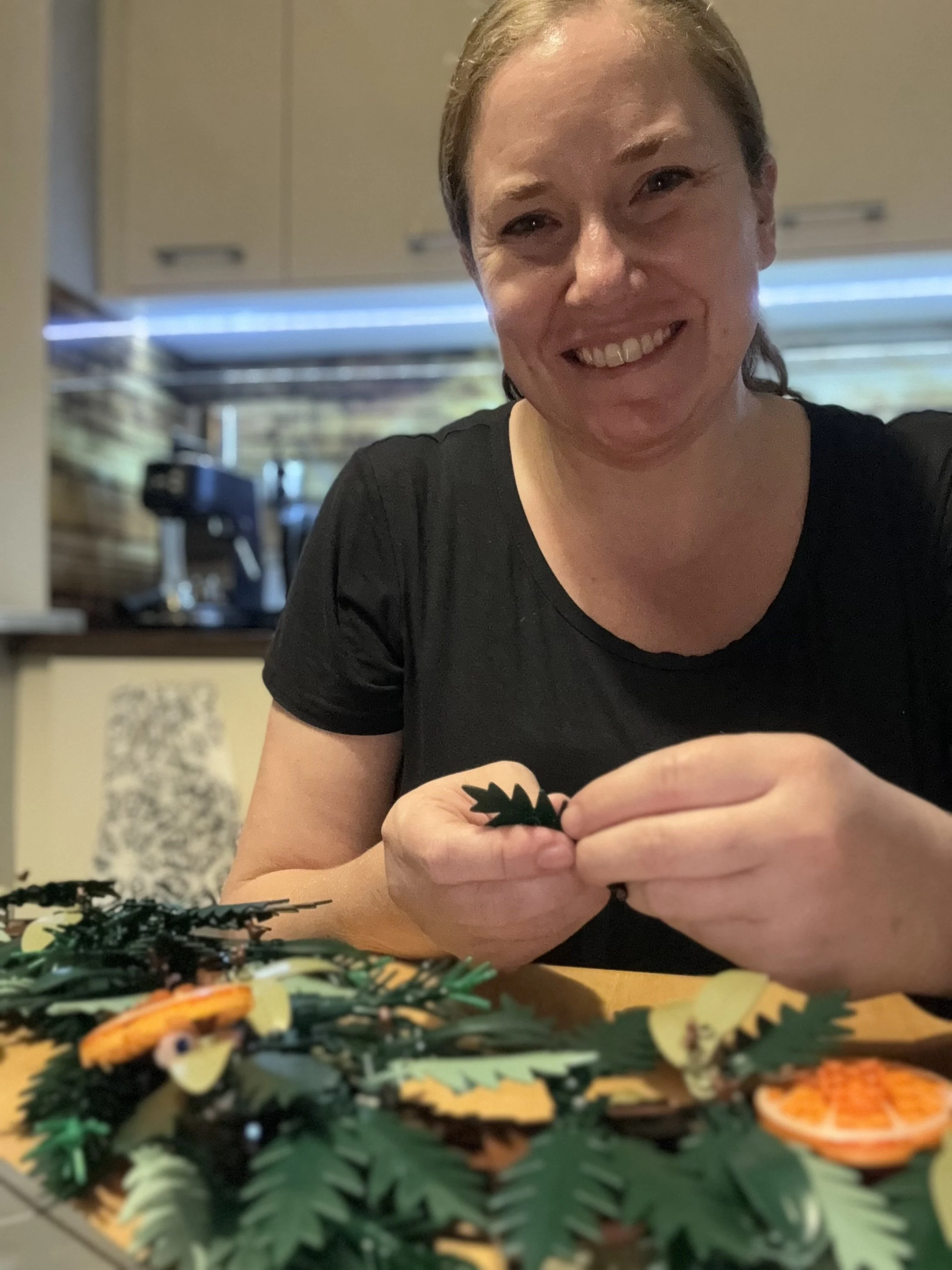 A woman smiling while decorating a table with various paper cutouts of leaves and oranges.
